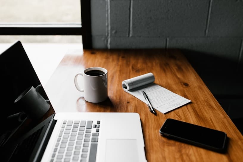 Laptop, notebook, and coffee on a meeting table